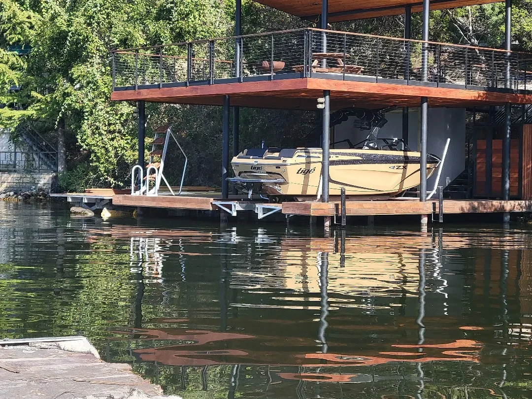 Covered dock with an upper deck, timber finishes and a boat slip viewed from the water.