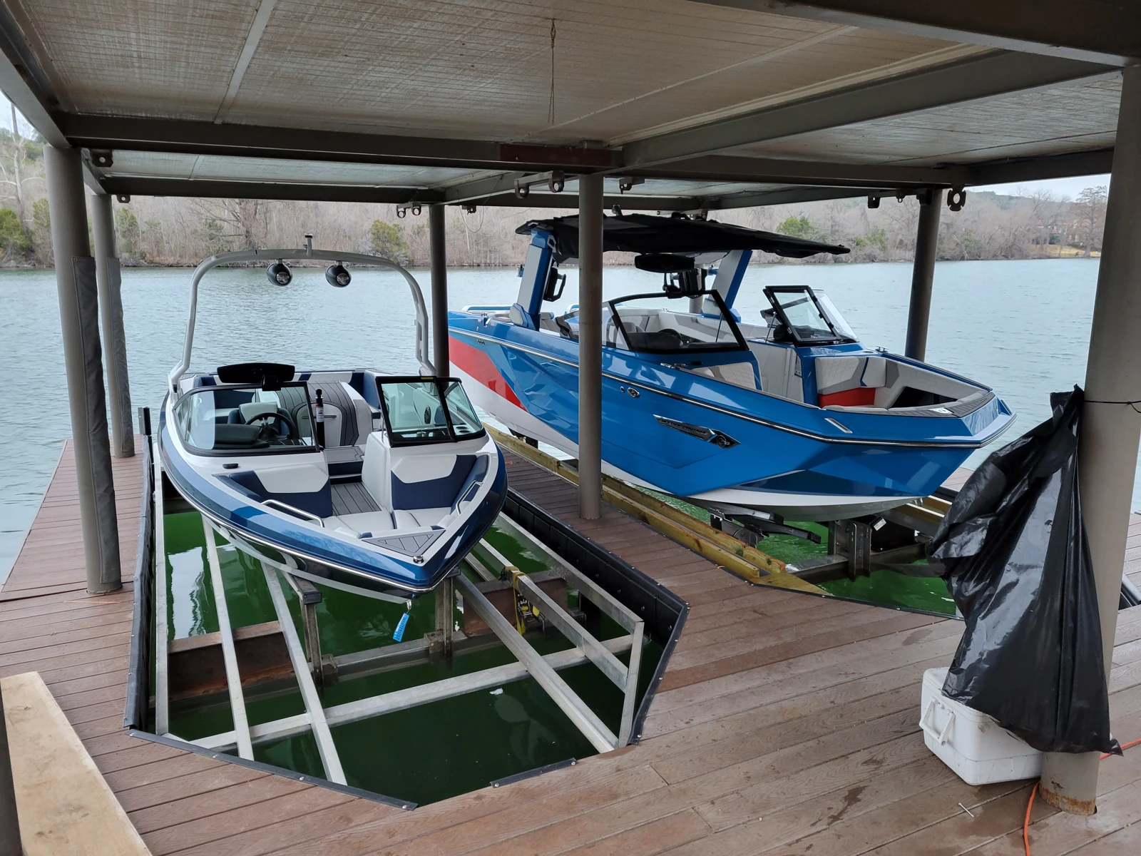 Two boats raised on integrated lifts within timber dock wells, with the lift frames visible.