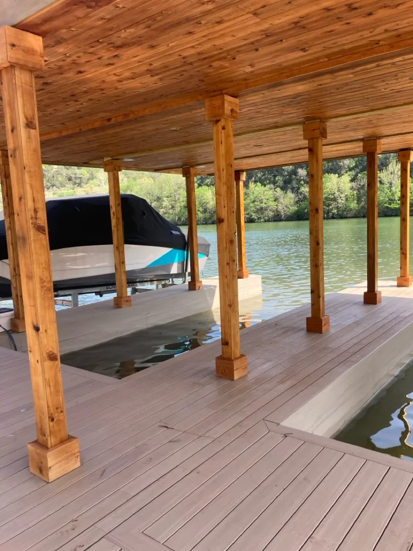 Timber-lined covered dock with composite decking beside the lake.